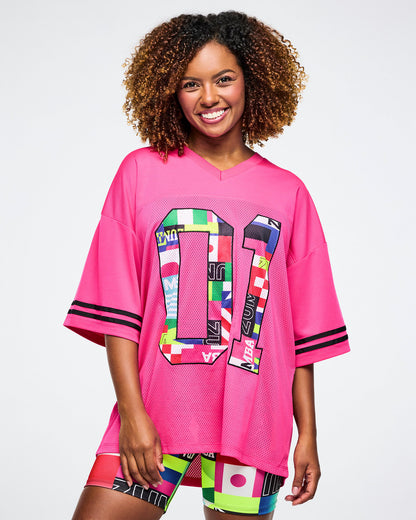Female model wearing a pink mesh jersey with colorful designs on a white background.