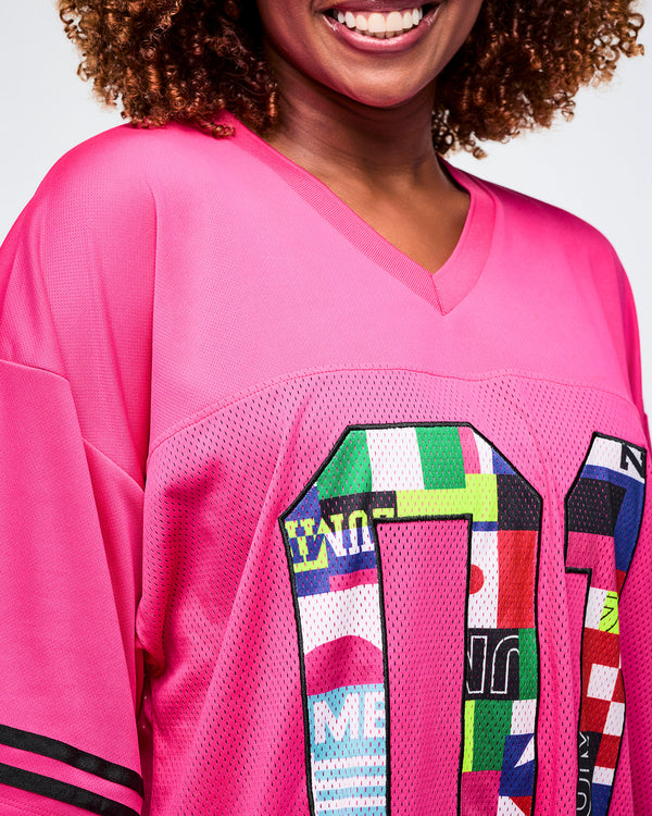 Close-up of a female model in a pink sports mesh top featuring an “01” with a colorful flag pattern.