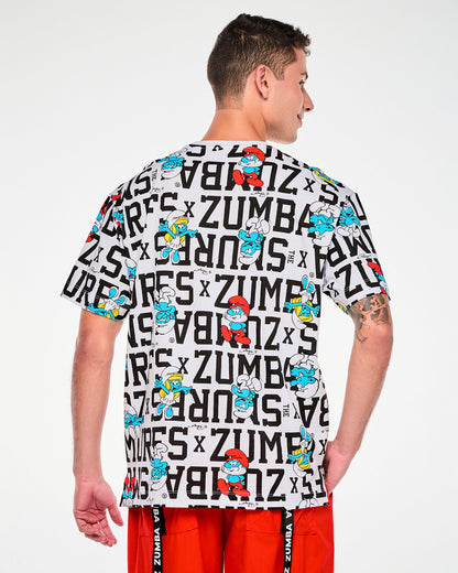 Back view of a male model in the white oversized top with the all-over Smurfs print, paired with red pants with black 'ZUMBA' drawcord straps.