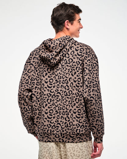 Shown from the back, a male model wears the brown leopard print hooded pullover sweatshirt with a relaxed, oversized fit and banded cuffs and hem.